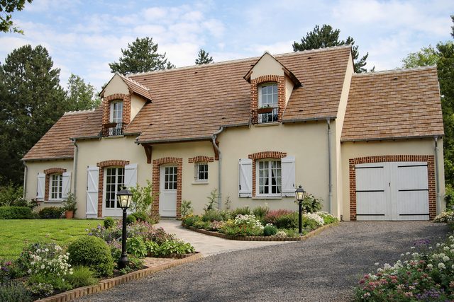 Maison de caractère avec lucarnes, briques et volets blancs